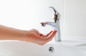 hand under faucet with low pressure water stream